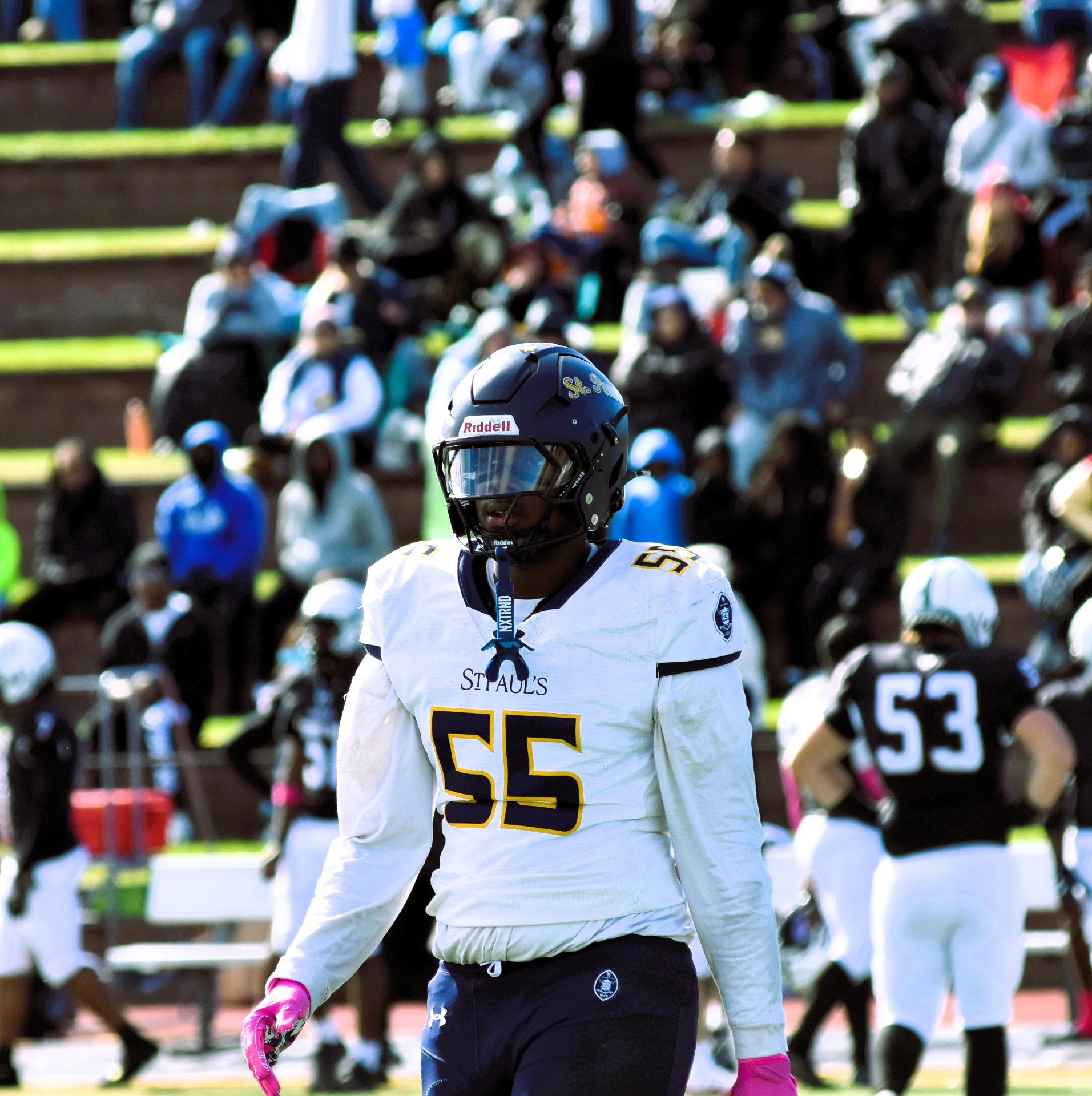 Crusaders number 55 walks across the field wearing pink gloves