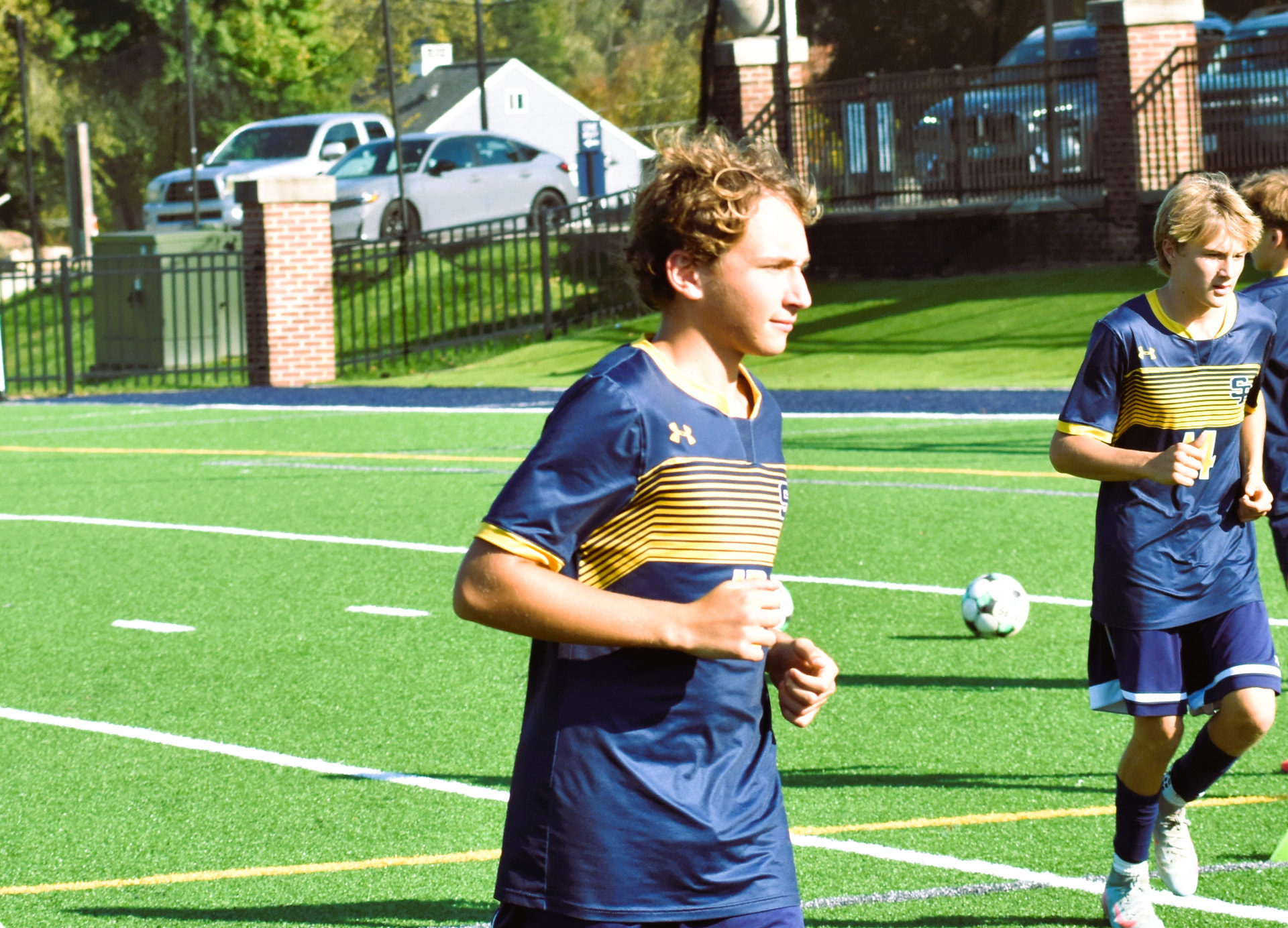 A JV Crusader warms up as teammates run behind him