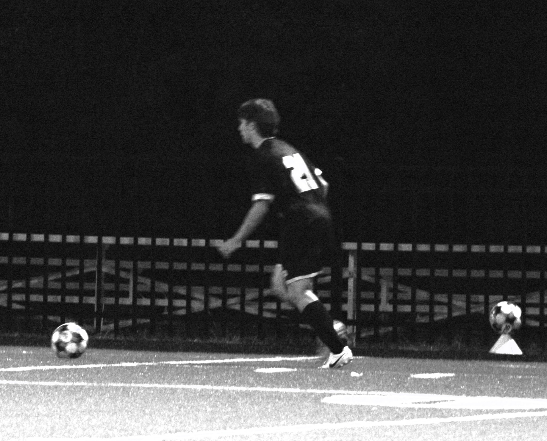 Player approaches the ball under the lights in black and white
