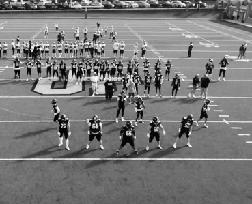 Aerial view of Mount Carmel linemen lined up in front of the team, black and white